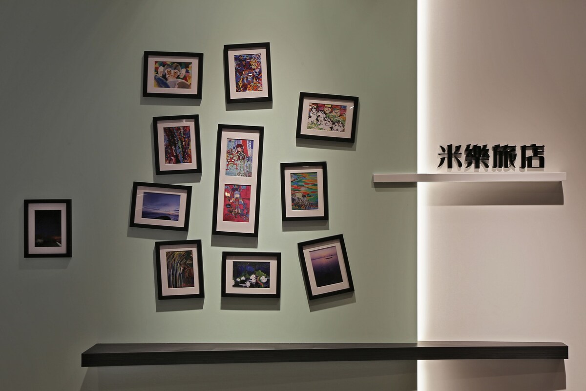 A wall with multiple framed artworks and a sign with Chinese characters.