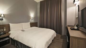 A modern hotel room with a large bed, bedside tables, a desk, and a mirror.