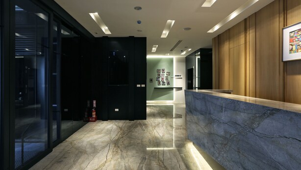A modern reception area with a marble floor, wooden paneling, and a reception desk. - Miller Inn (Taichung)