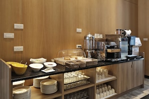 A buffet area with various food items, a coffee machine, and a self-service beverage station.