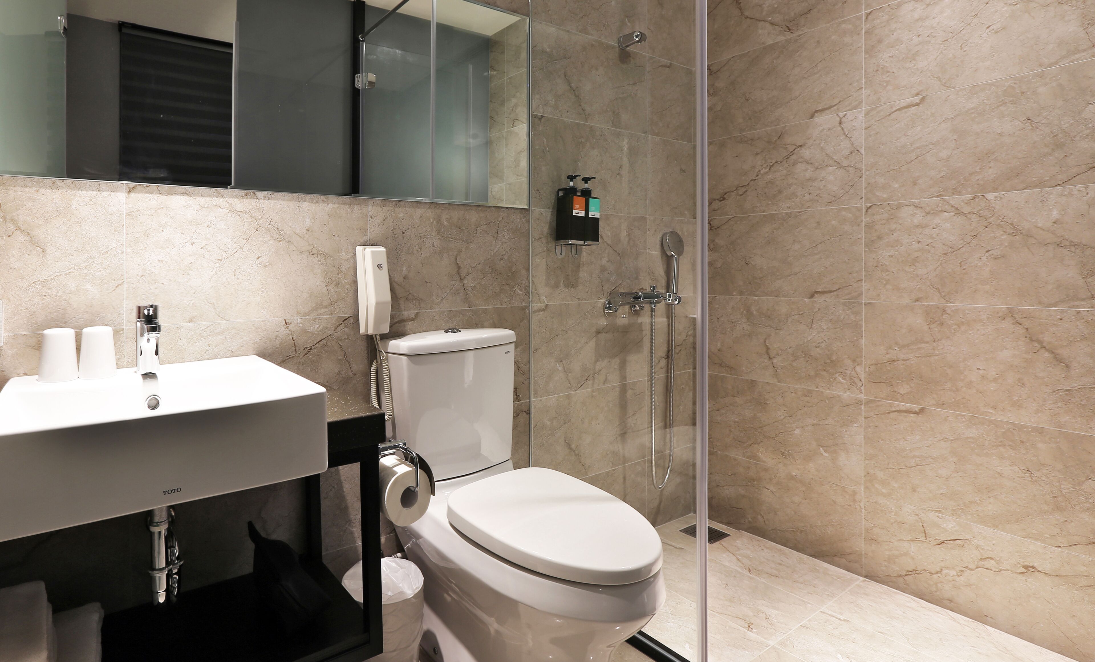 A modern bathroom with a toilet, sink, and glass-enclosed shower.