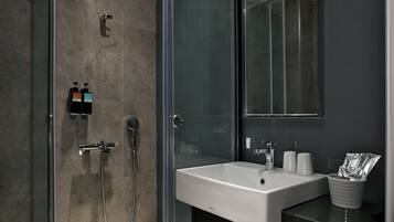 A modern bathroom with a glass-enclosed shower, a white sink, and a large mirror.