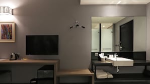 A modern hotel room with a flat-screen TV, a large mirror, a wooden bench, a sink, and a bed. - Miller Inn (Taichung)