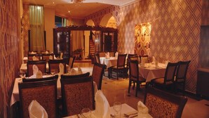 Un restaurante con varias mesas y sillas, intrincados diseños en las paredes y candelabros.