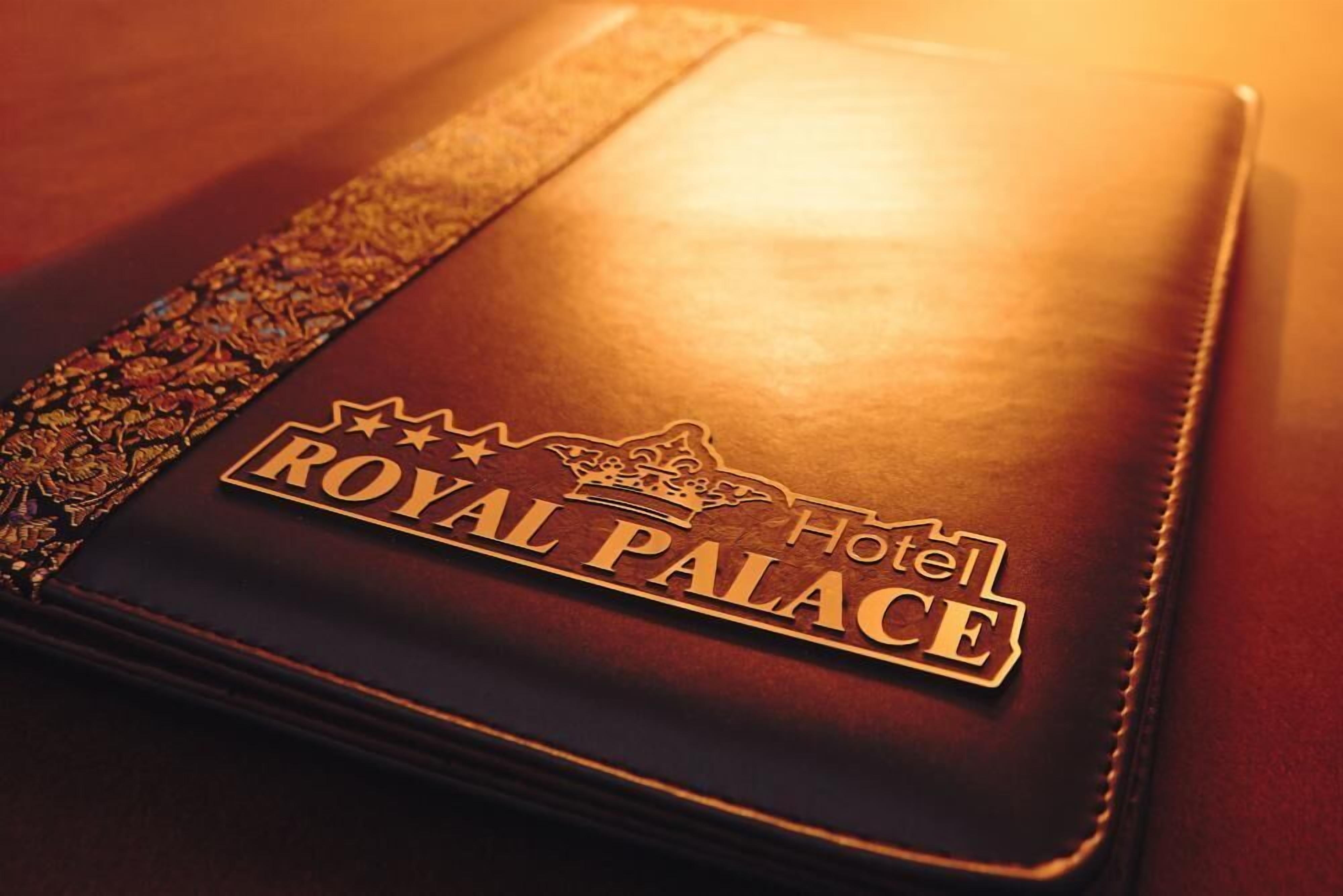 Um livro encadernado em couro com o logotipo em dourado do Royal Palace Hotel.