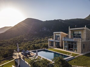 A modern house with a swimming pool, stone exterior, and a view of mountains. - Kastraki Epavlis (Corfu)