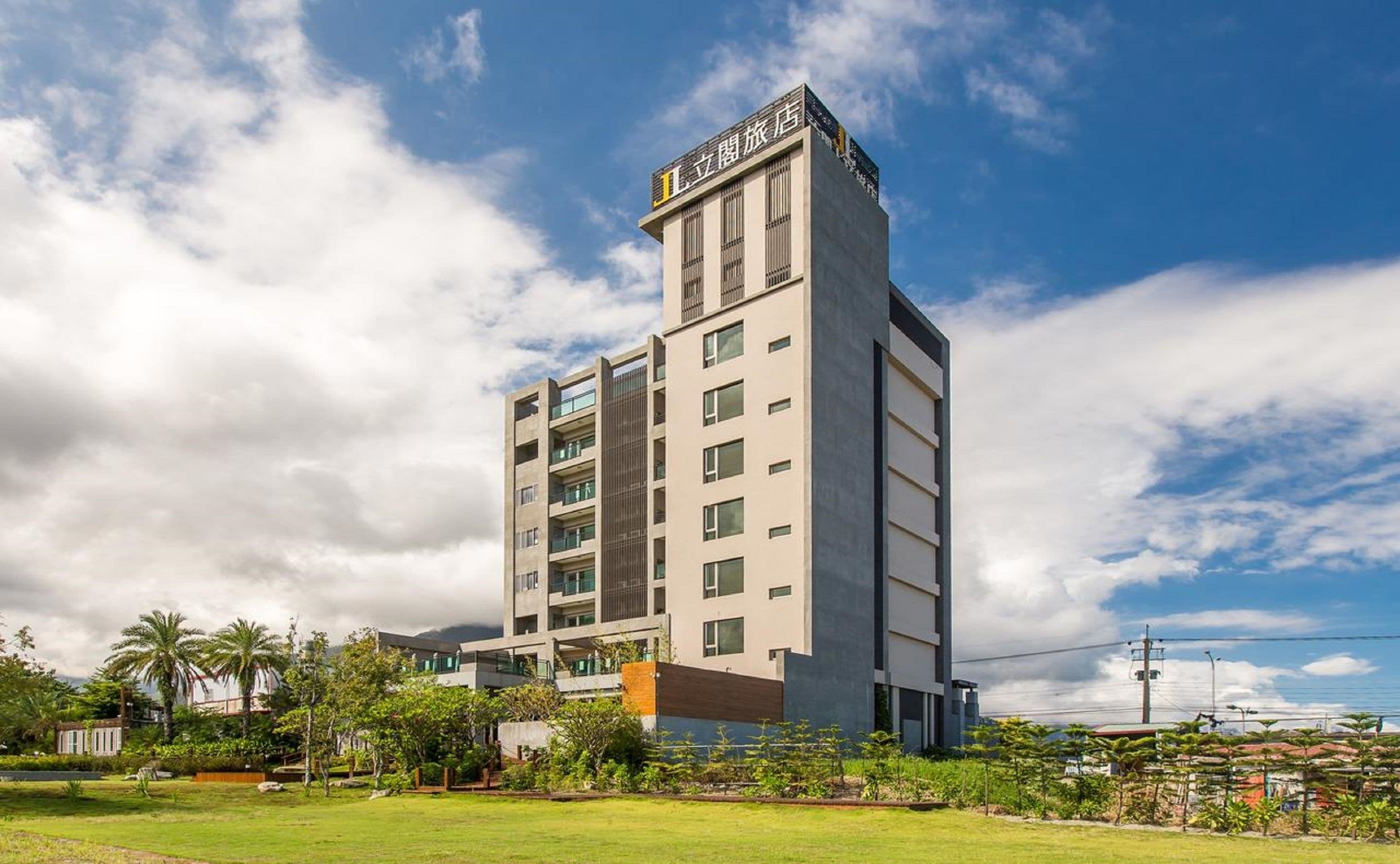 A multi-story hotel with a modern design, featuring a prominent entrance and a rooftop terrace.