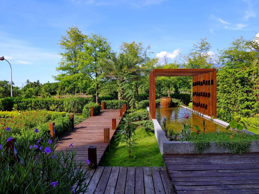 A wooden boardwalk leading to a water feature with a wooden archway.