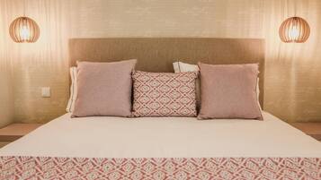A neatly made bed with a patterned bedspread and three pillows, two of which are plain and one with a geometric design.