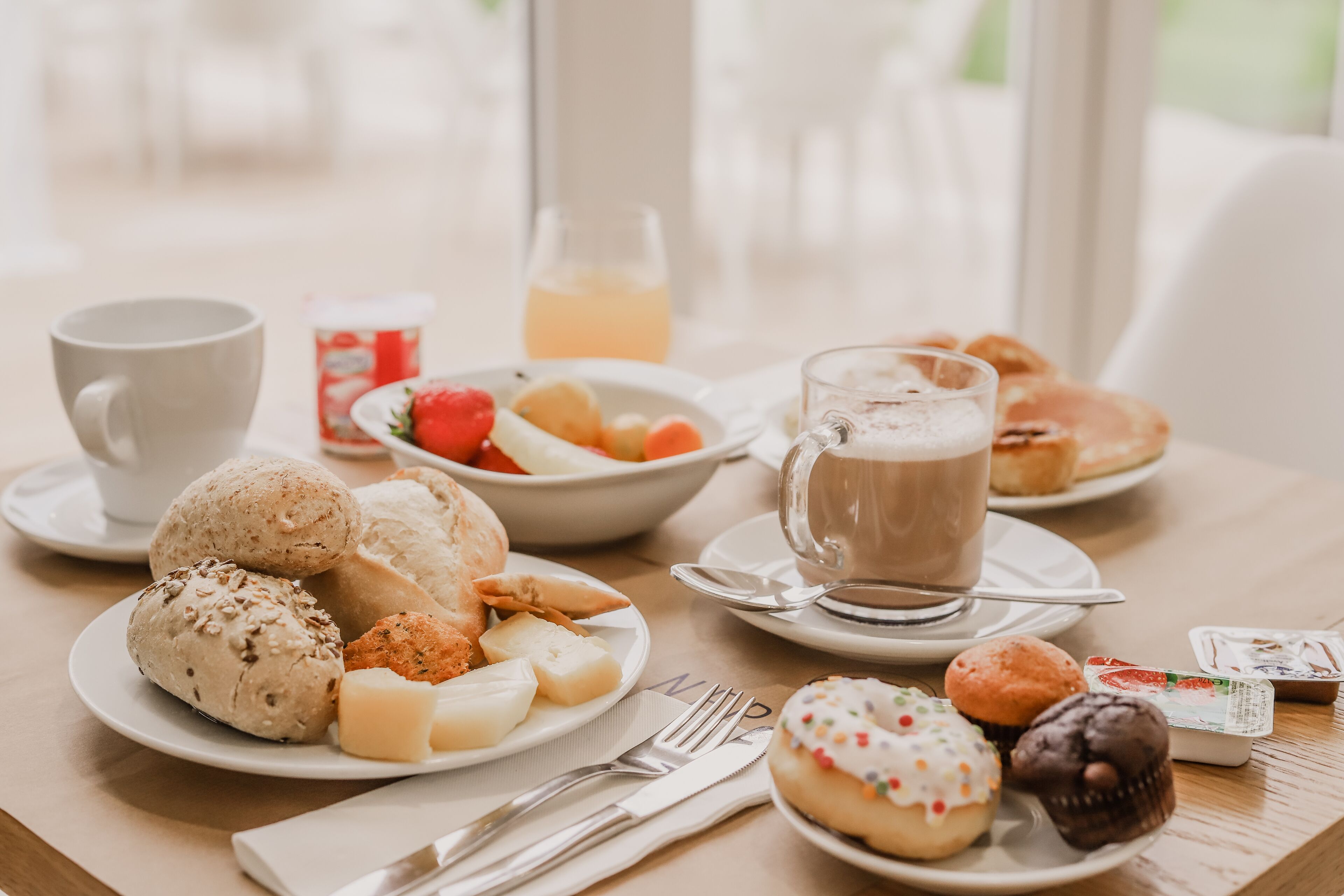Una mesa de desayuno con pasteles, frutas y bebidas.