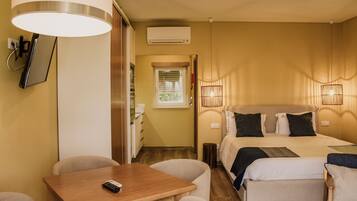 A hotel room with a bed, bedside lamps, a desk with a chair, and a small table with a remote control.