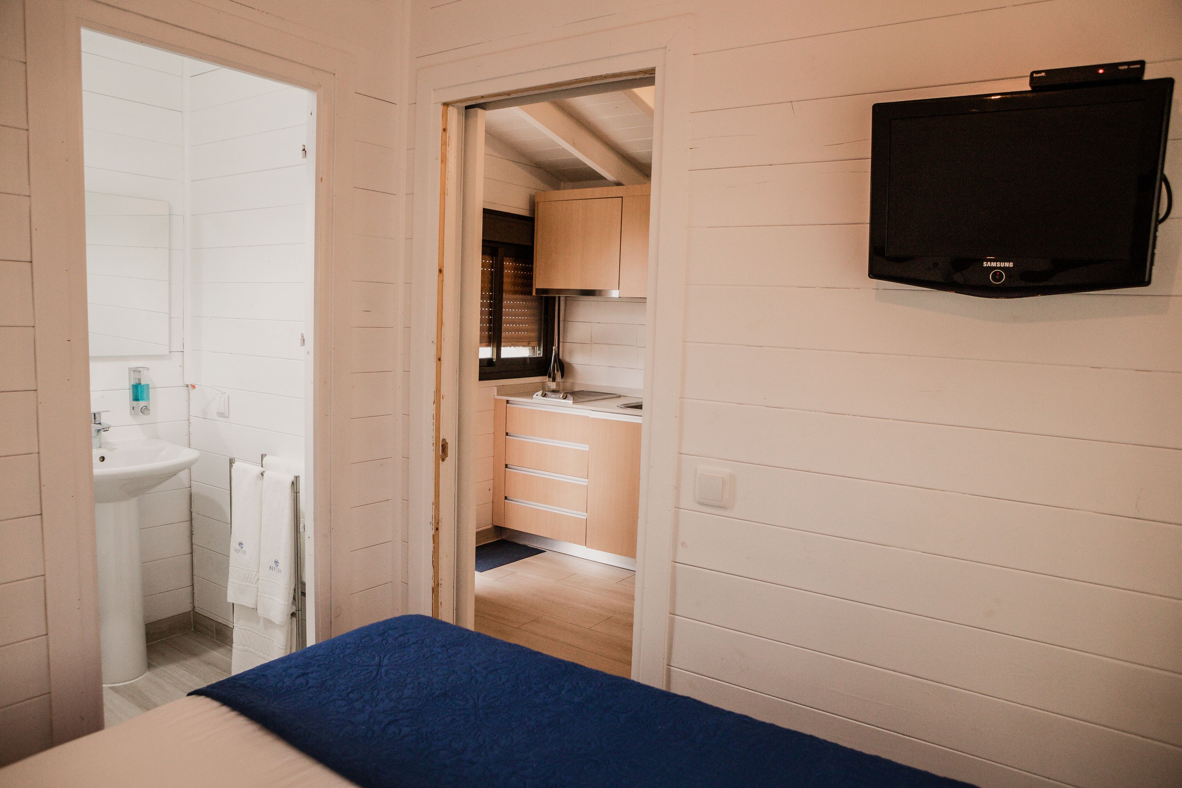 Een kamer met een bed, een wastafel en een aan de muur bevestigde televisie.