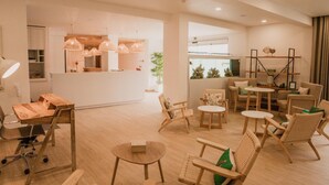 A modern hotel lobby with wooden furniture, a reception desk, and a dining area. - Hotel Neptuno (Peniche)