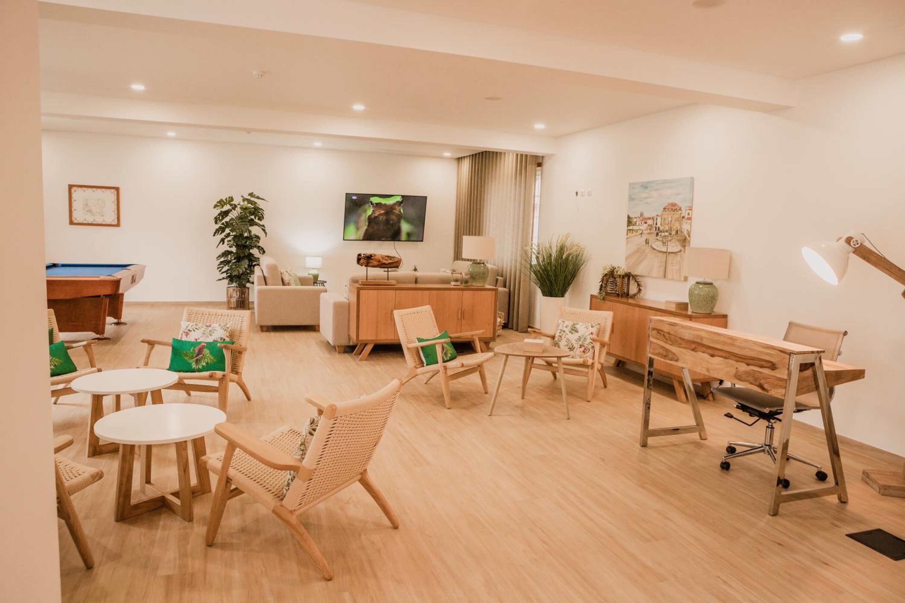 A spacious living area with a pool table, comfortable seating, a wooden desk, and a television.
