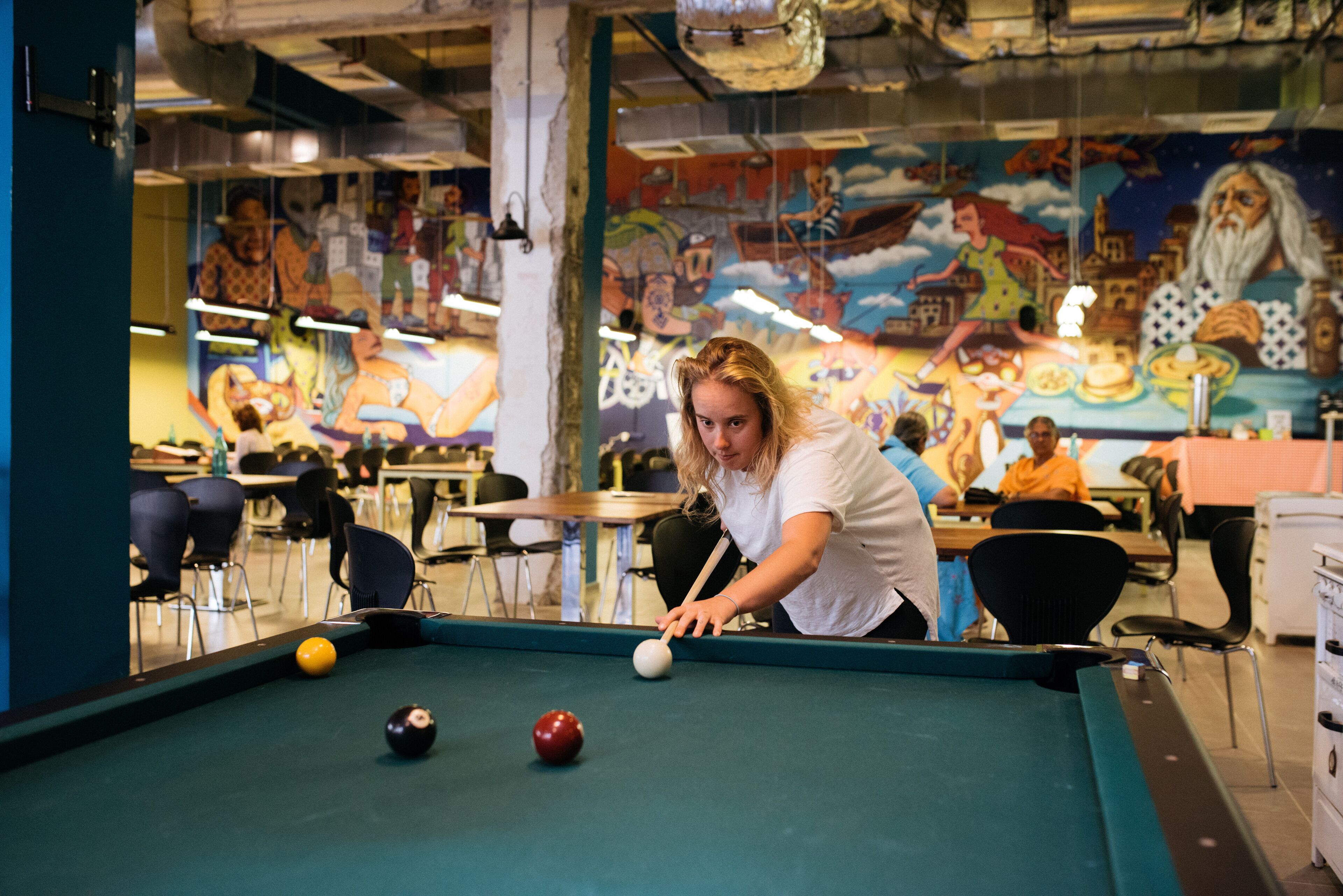A pool table in a room with a mural on the wall.