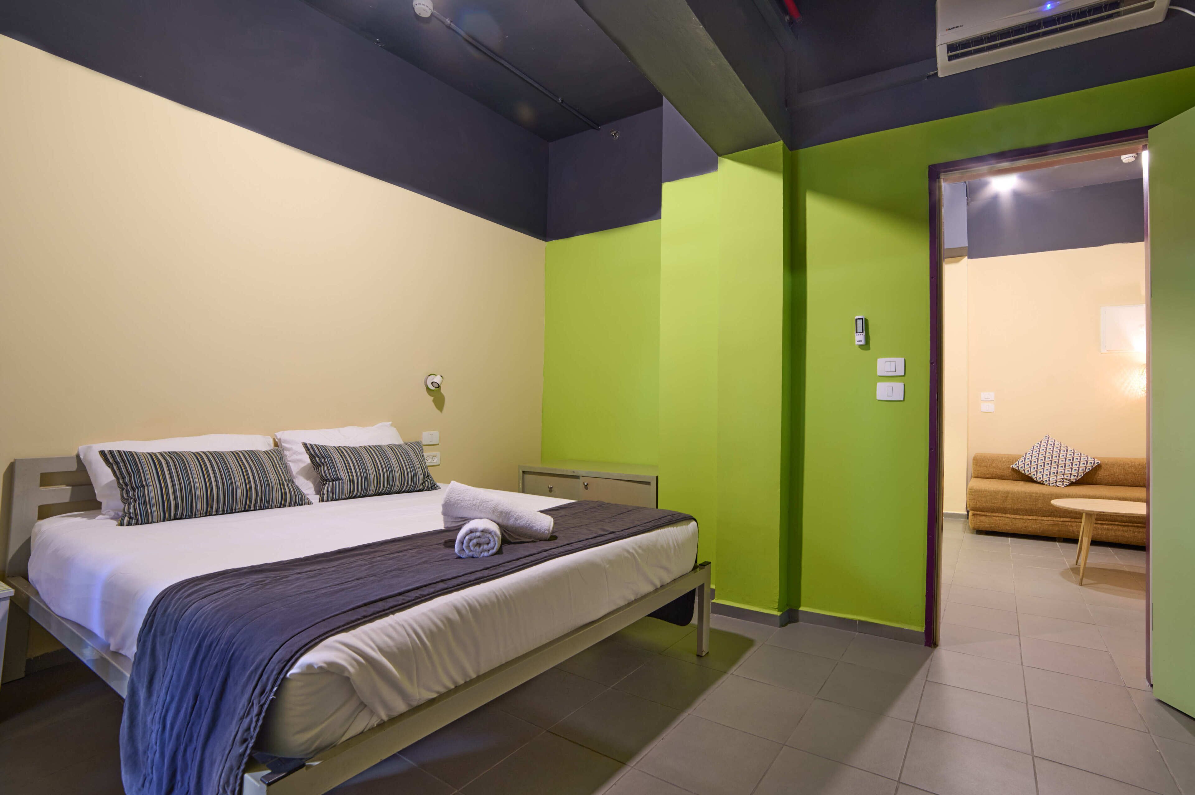 A hotel room with a bed, bedside table, and a green wall.
