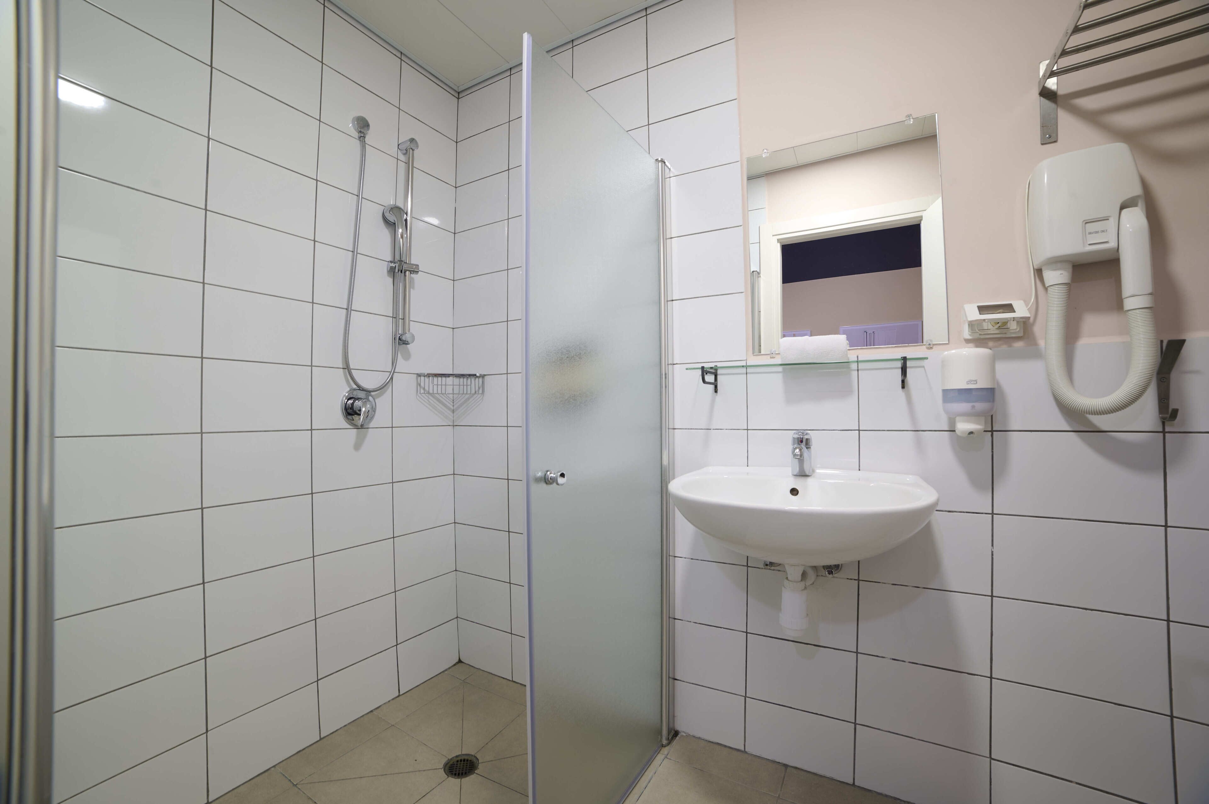 A bathroom with a glass shower enclosure, a white sink, and a mirror above it.