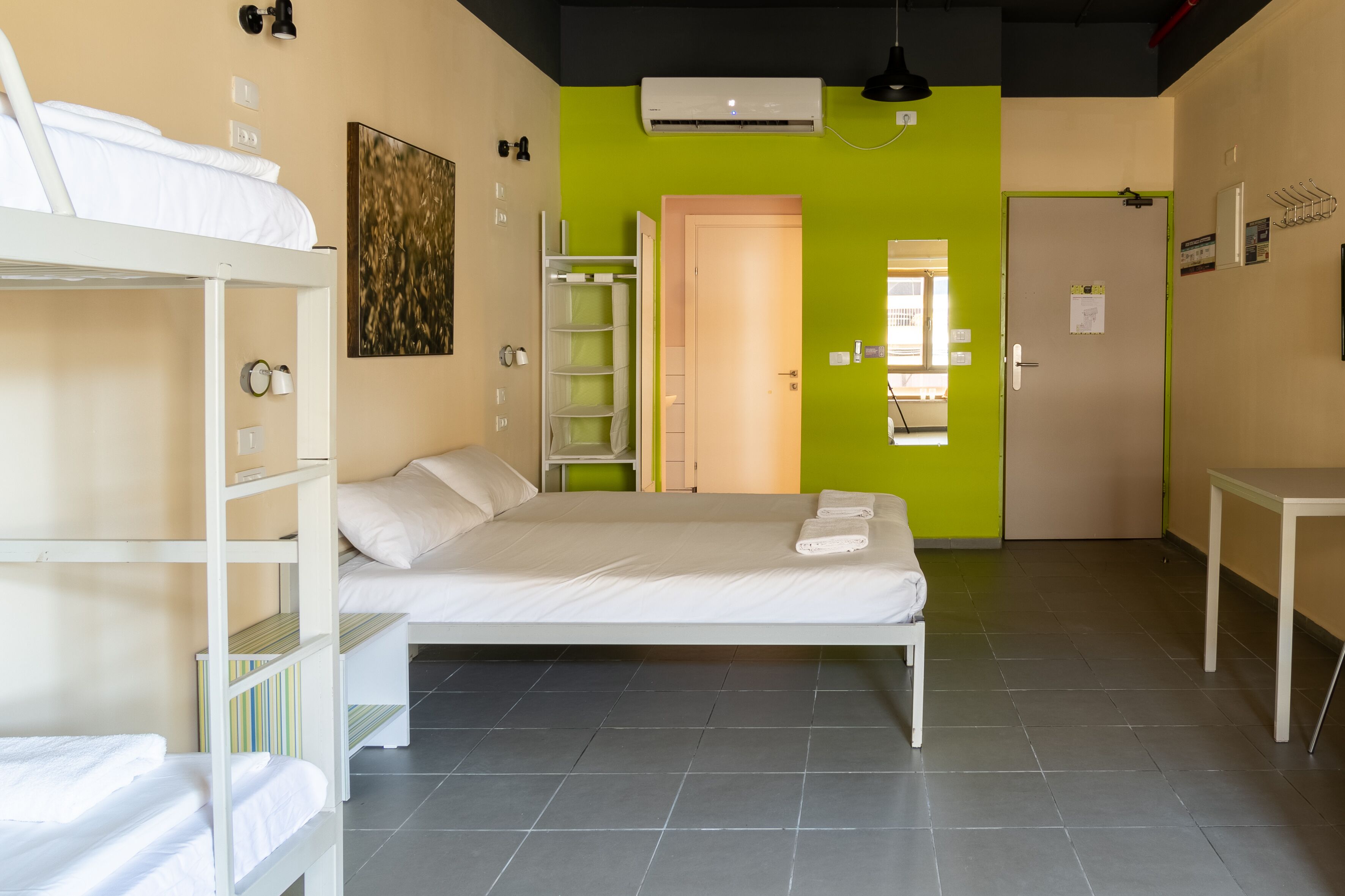 Une chambre avec des lits superposés, un bureau et un mur vert.
