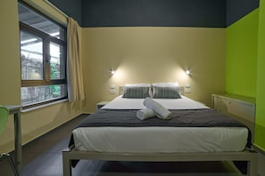 A hotel room with a bed, bedside lamps, a window with curtains, and a view of the outside. - Abraham Tel Aviv (Tel Aviv)