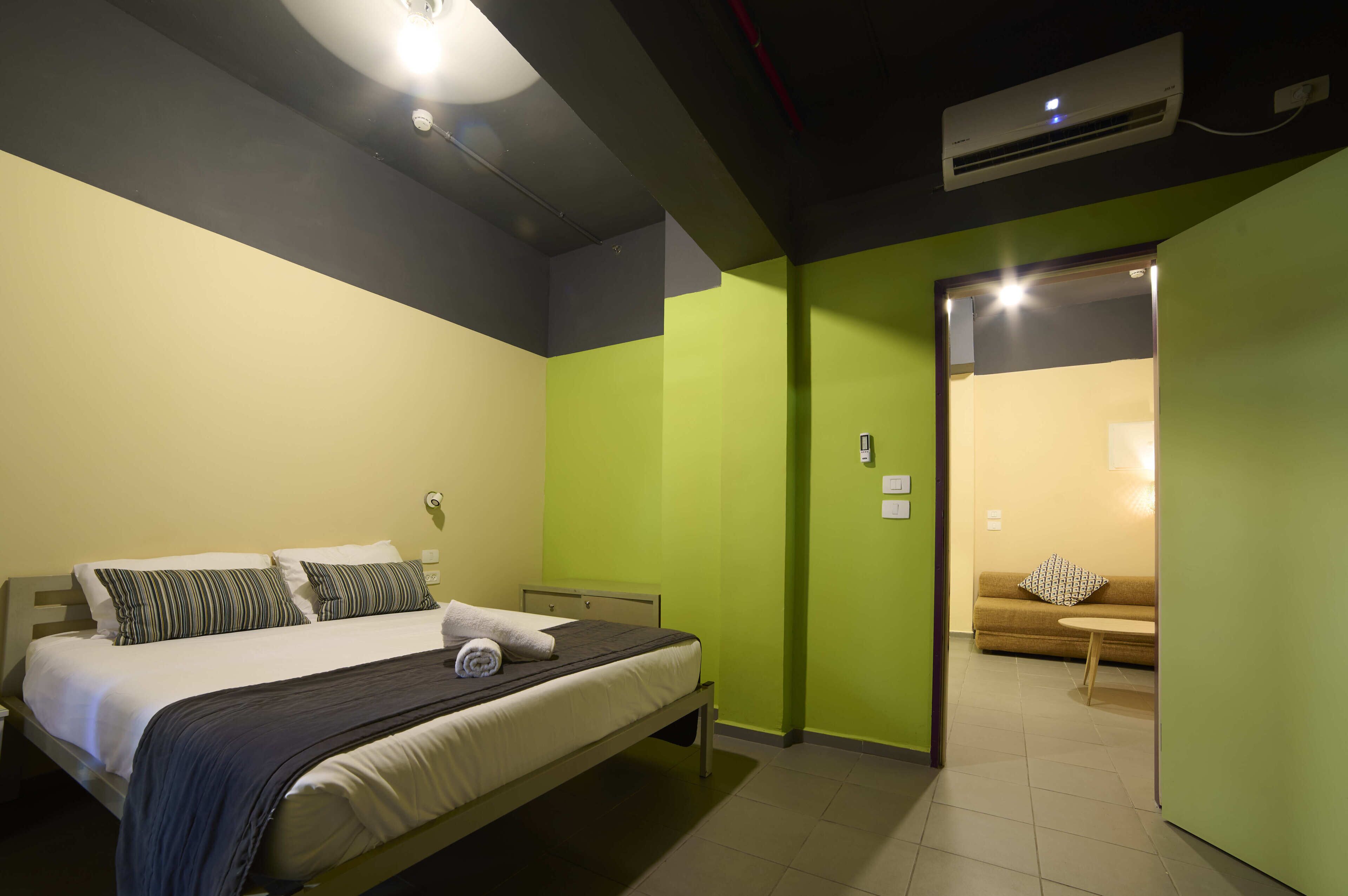 A hotel room with a bed, a sofa, and a door leading to another room.