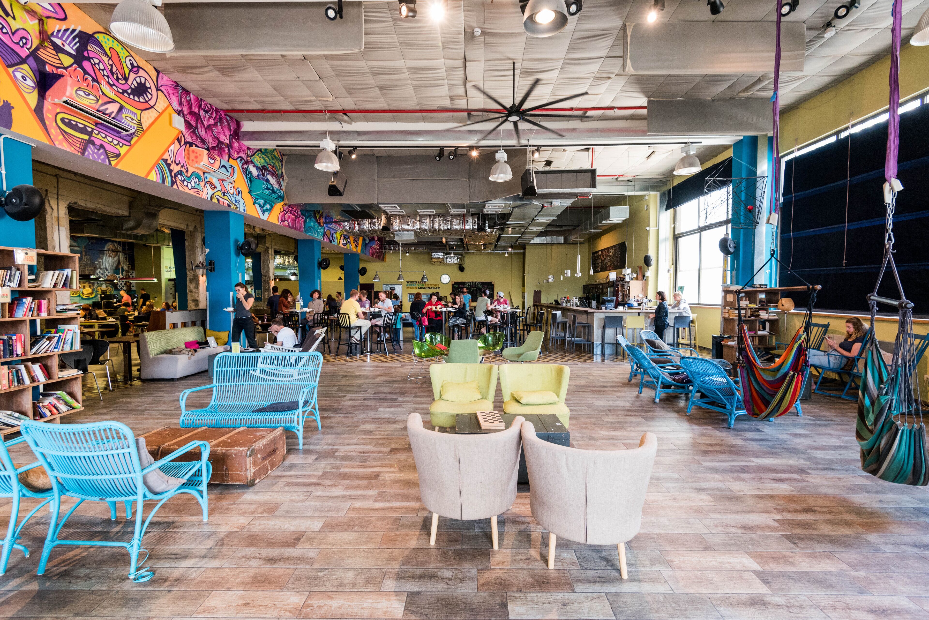 A spacious indoor area with a variety of seating options, including chairs and sofas, and a large mural on the wall.