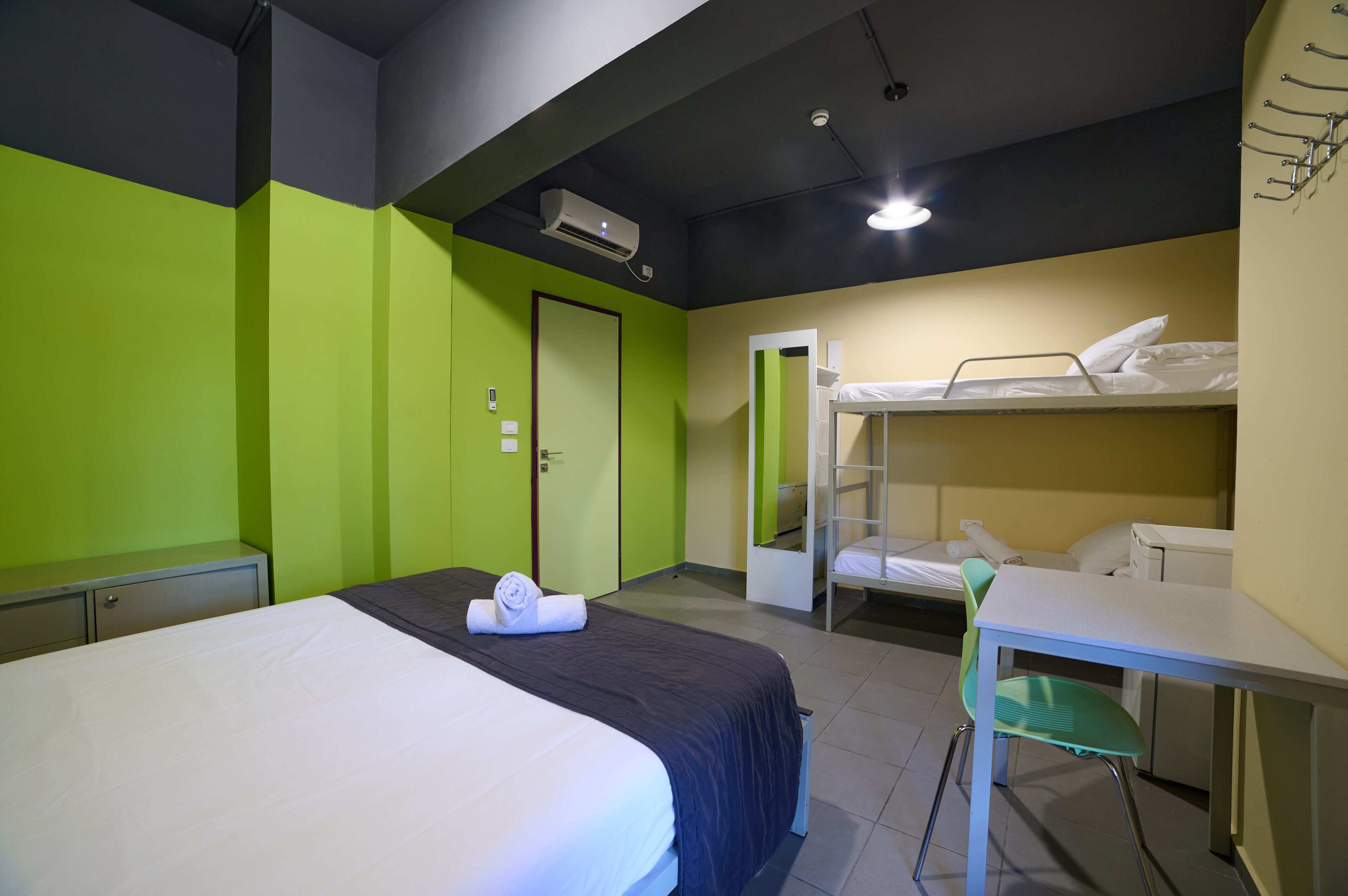 Habitación de hotel con una cama individual, un escritorio y una litera.