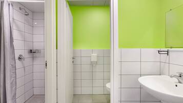 Ein Badezimmer mit weißen Fliesen, einer grünen Akzentwand, einer Dusche und einem Waschbecken.