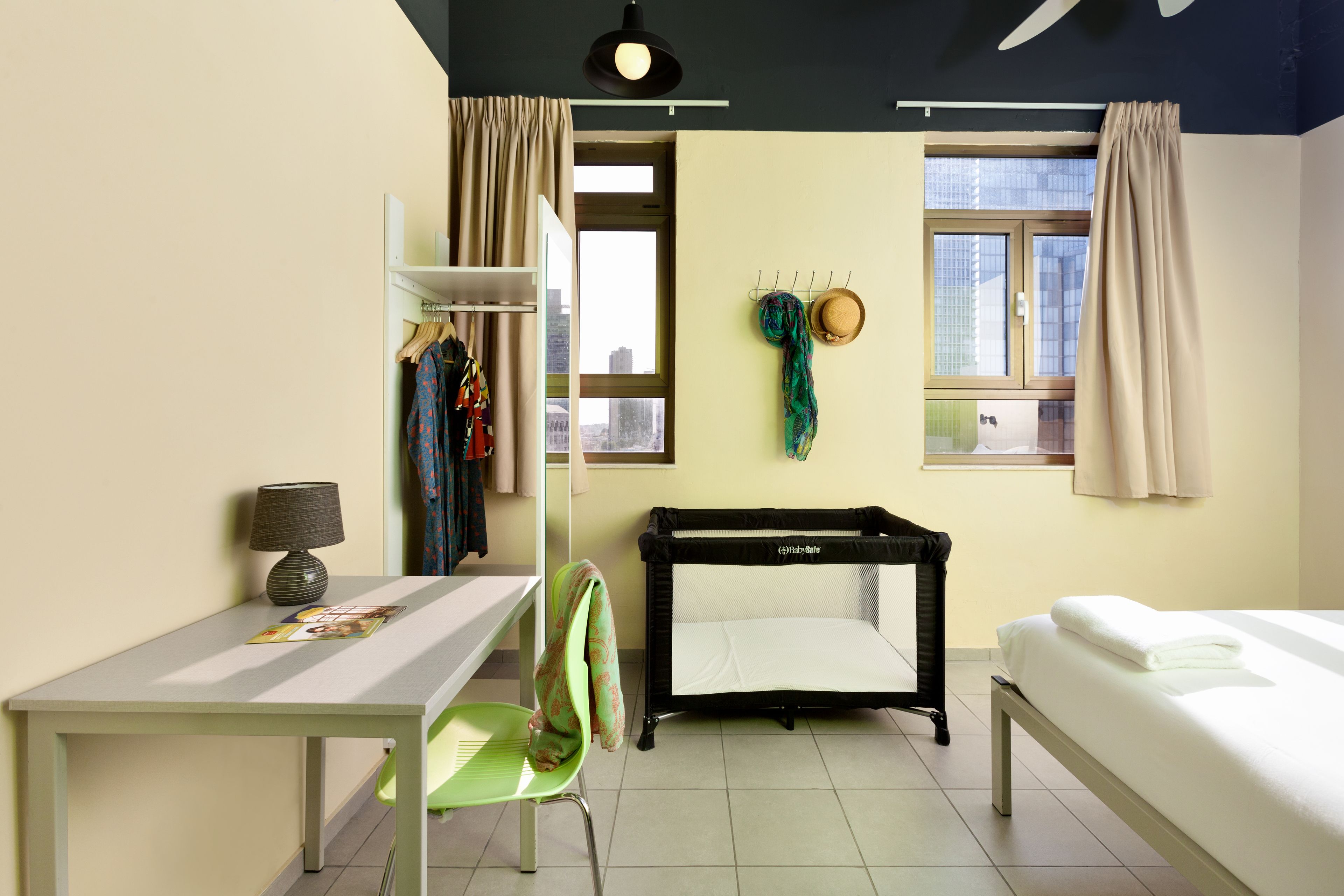 A room with a bed, a desk, a chair, a small table, and a window.
