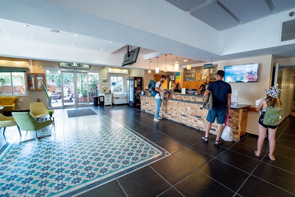 A modern hotel lobby with a reception desk, seating area, and a large screen. - Abraham Tel Aviv (Tel Aviv)