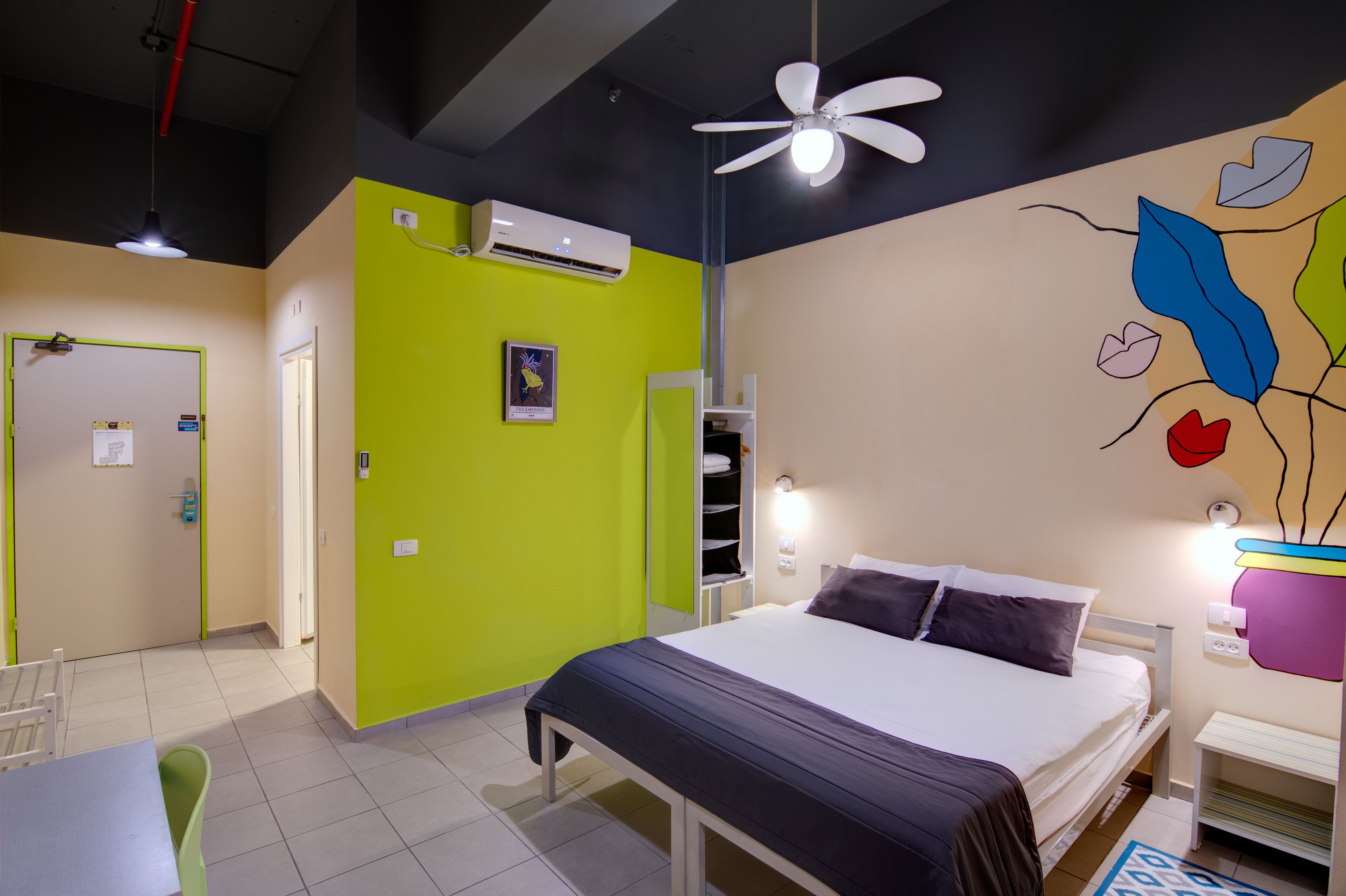 Una habitación de hotel con cama, mesita de noche y ventilador de techo.