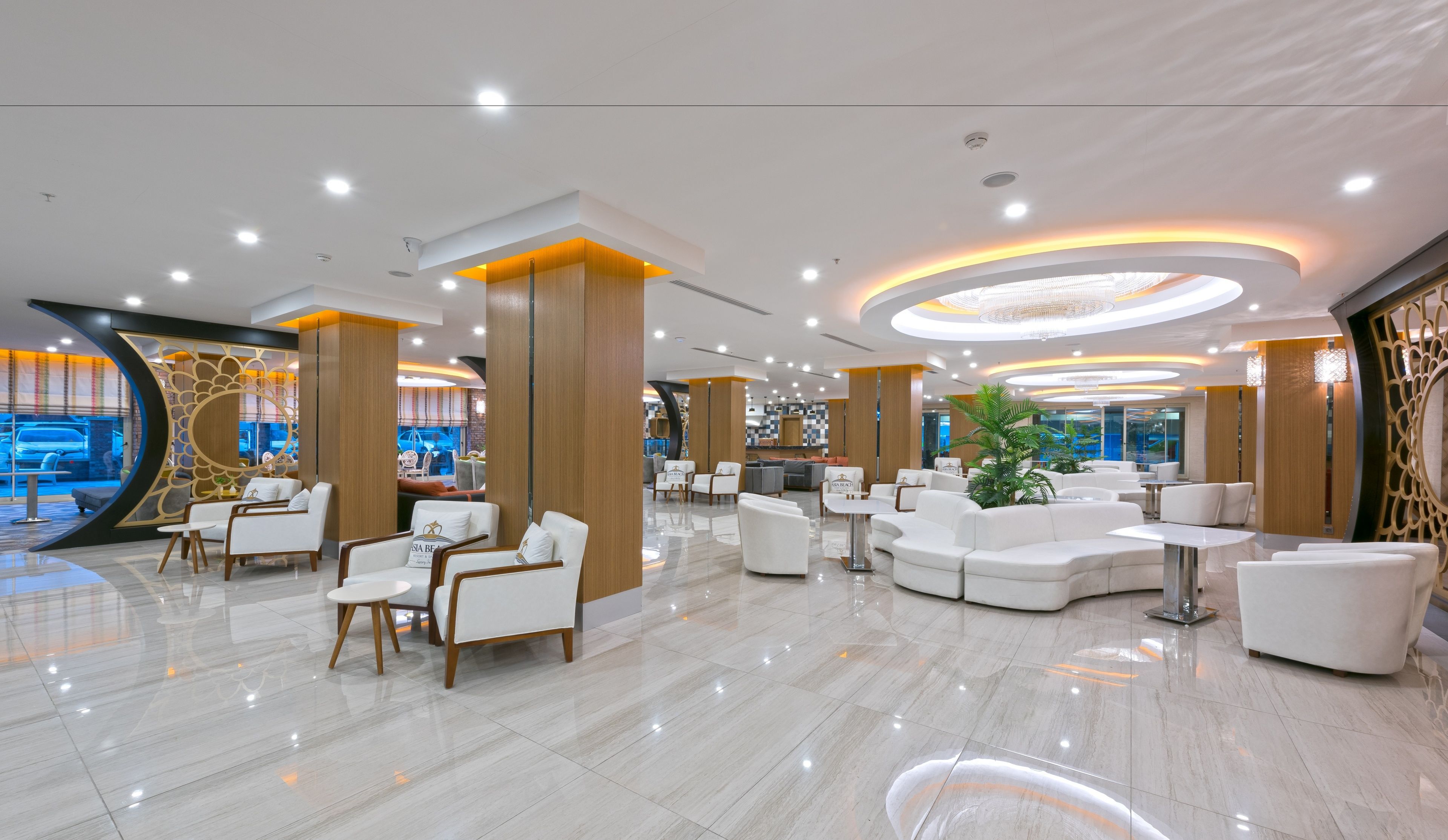 En moderne hotellobby med hvide møbler, et centralt siddeområde og udsigt til gaden.