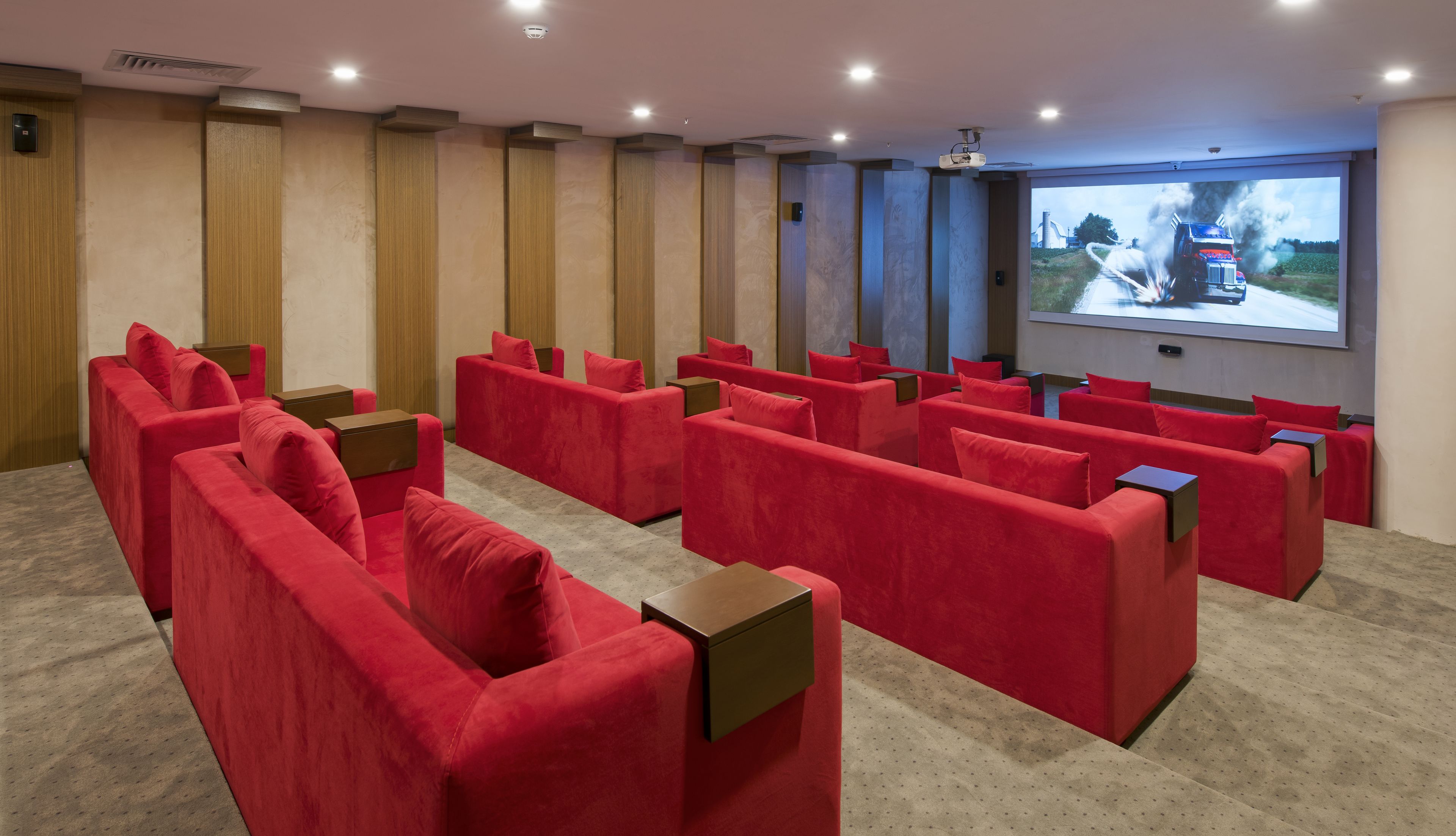 A modern cinema room with red seating and a large screen displaying a train.