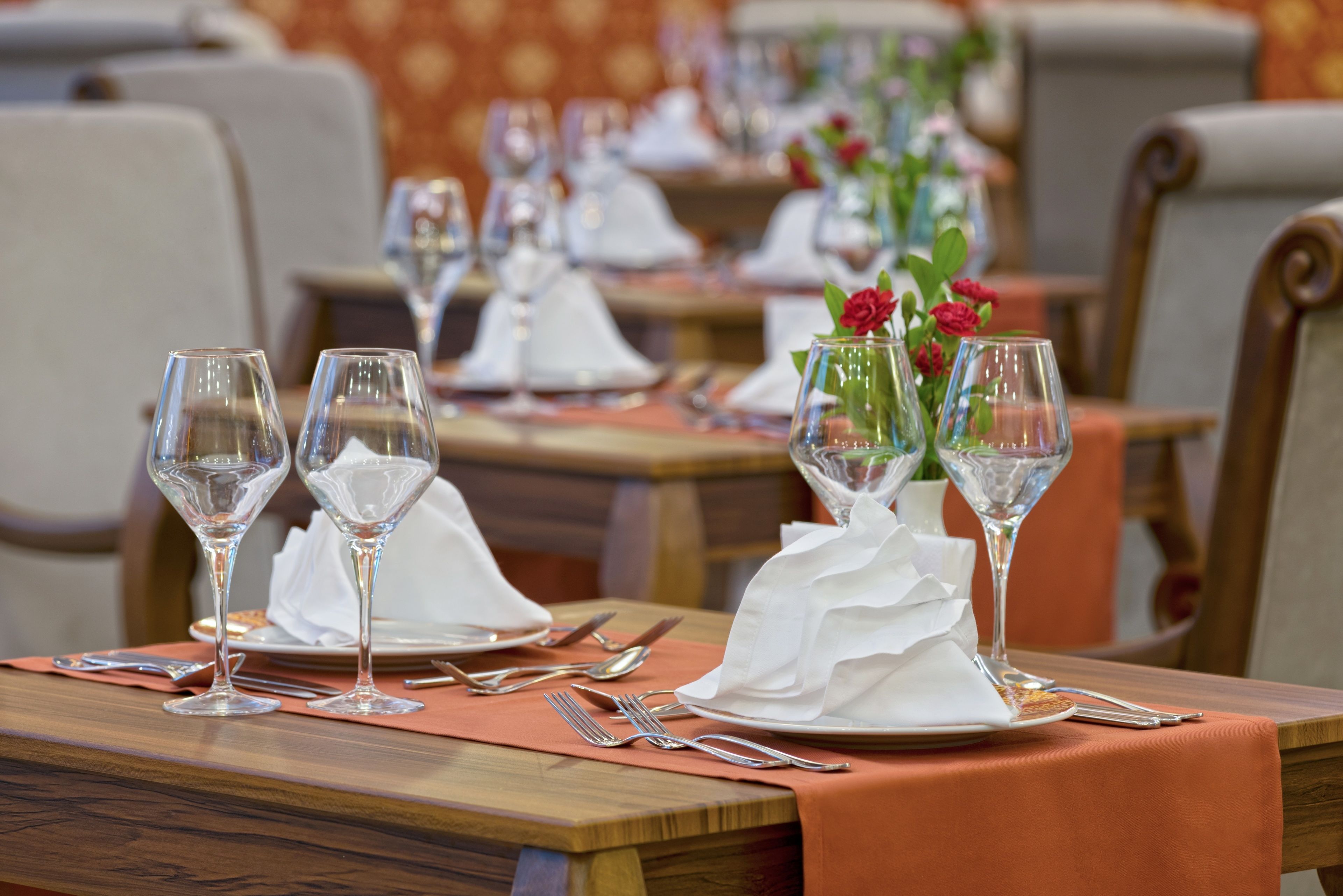 A restaurant setting with tables set for dining, featuring clear glassware, white napkins, and floral centerpieces.