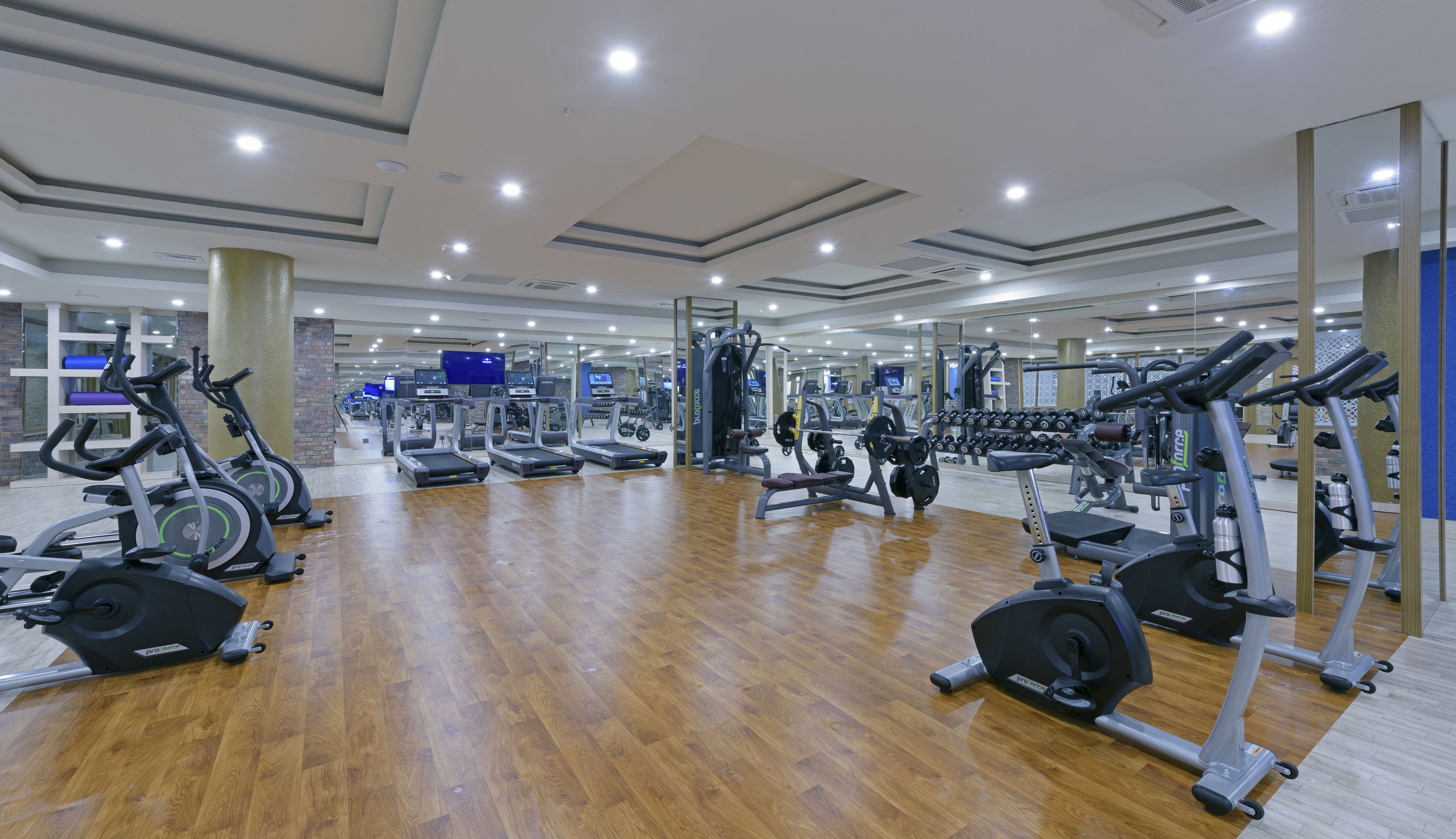 Un gimnasio con cintas de correr, elípticas y equipo de levantamiento de pesas.