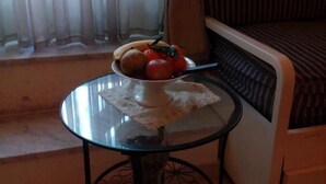 Uma pequena mesa redonda com um sousplat de renda branca, uma tigela de fruta e um copo de água.