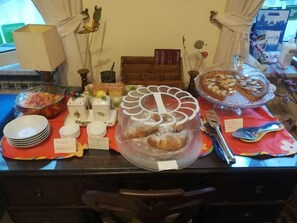 A buffet table with various food items, including a large cake, pastries, and a fruit bowl. - B&B Cupole e Campanili (Naples)