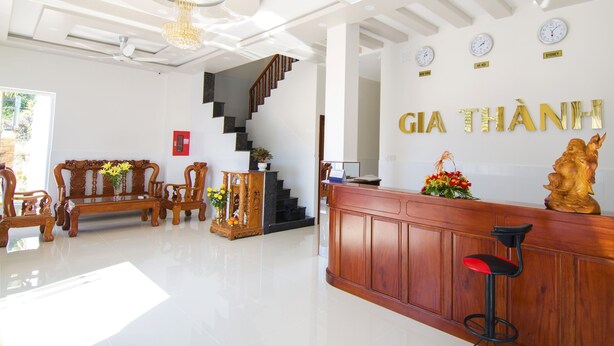A hotel lobby with a reception desk, a staircase, and a seating area with a sofa and chairs. - Gia Thanh Guest House (Phu Quoc)