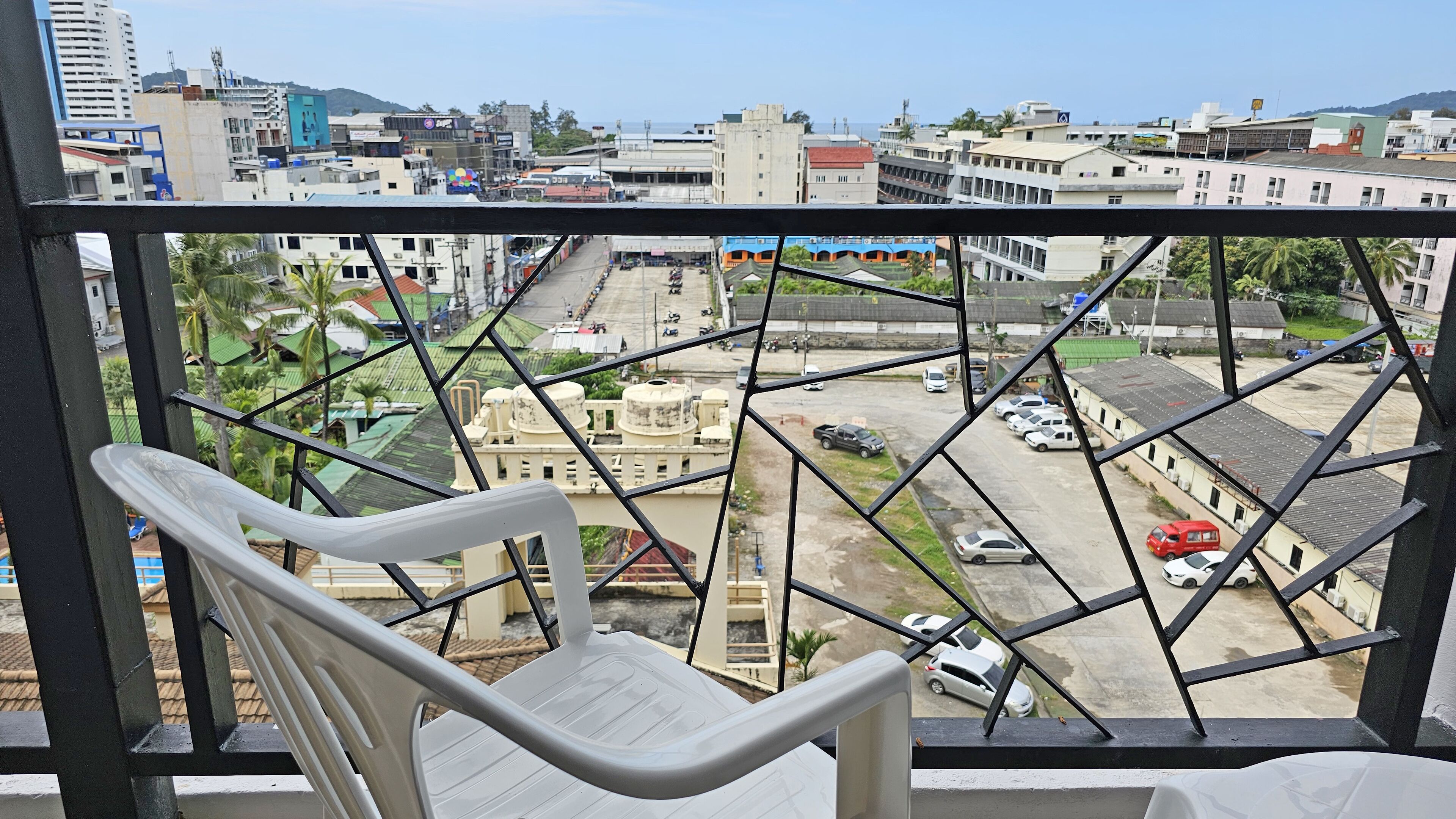 A balcony with a view of a cityscape, including buildings and parked cars.