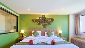 A hotel room with a large bed, two nightstands, a shower, and a green wall with a decorative cross pattern.