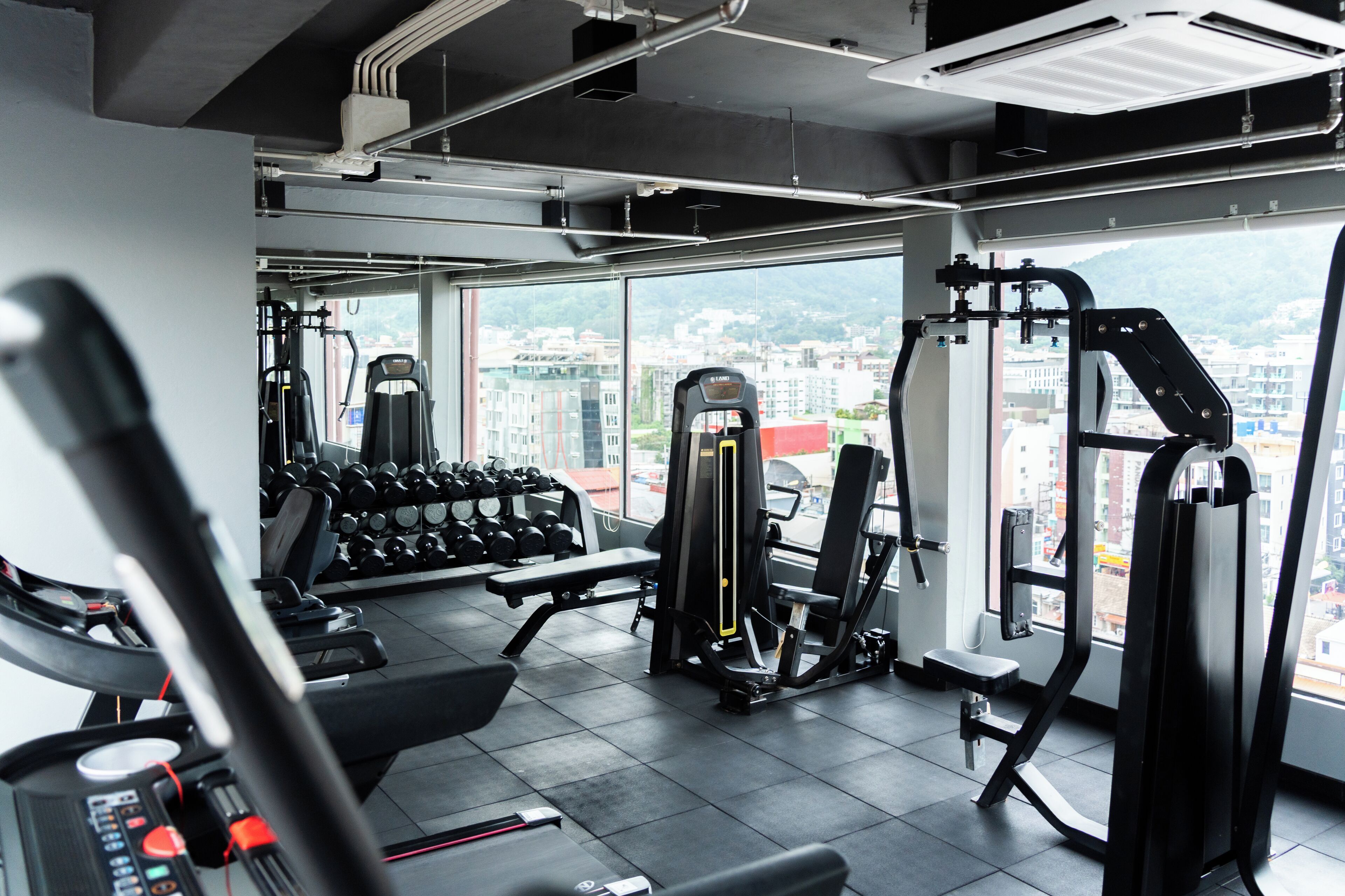 Un gimnasio con equipo de ejercicio, una banca y una pared de mancuernas.