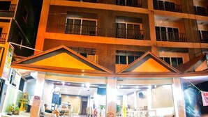 A multi-story hotel with a central atrium, balconies, and a well-lit entrance. - Joy Residence (Pattaya)