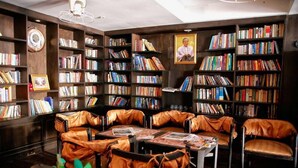 A library with bookshelves, leather chairs, and tables. - Joy Residence (Pattaya)