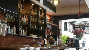 A bar area with wooden stools, shelves stocked with bottles, and a hanging light fixture. - Joy Residence (Pattaya)