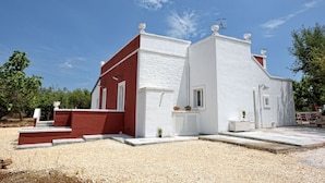 A two-story building with a red and white facade, a small front porch, and a gravel driveway.