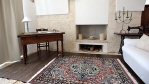 A cozy room with a wooden table, a patterned rug, a white sofa, and a sewing machine.