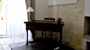 A room with a wooden table, a chair, a lamp, and a vase.