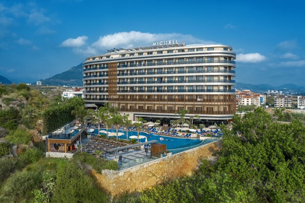 Un grand hôtel doté d’une piscine, de nombreux balcons et offrant une vue sur le paysage environnant.