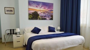 A bedroom with a bed, a nightstand, a lamp, a painting, and a window with curtains. - B&B Bagheria (Bagheria)