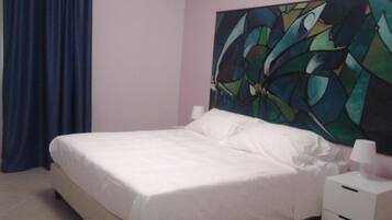 A bedroom with a bed, a nightstand, and a large abstract painting on the wall.