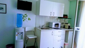 A compact kitchen with white cabinets, a microwave, a toaster, and a water dispenser. - B&B Bagheria (Bagheria)